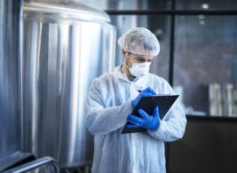 Concentrated technologist expert in white suit controlling production in food factory. Concentrated technologist expert in white suit controlling production in food factory.